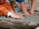 Bild vergrößert sich per Mausklick: Kinderhände im Boden