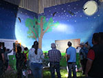 Bild vergrößert sich per Mausklick: Batnigth 2022 - Dunkler Raum mit Nachtlandschaft gemalten Wänden und Fledermäuse und Teilnehmer, die schauen und Bilder aufnehmen