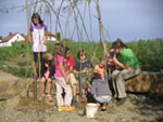 Bild vergrößert sich per Mausklick;Kinder zusammen mit einer Lehrerin vor Holzästen