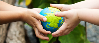 Das Bild zeigt zwei Kinderhände, die einen kleinen Globus halten.